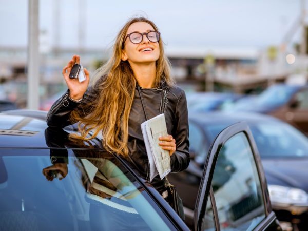 Happy woman with a rental car